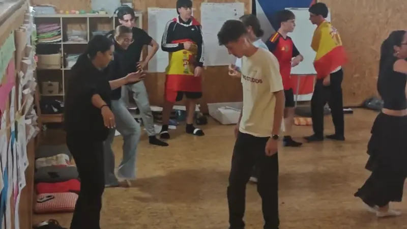 Participantes bailando en la sala con banderas de España durante la noche intercultural española