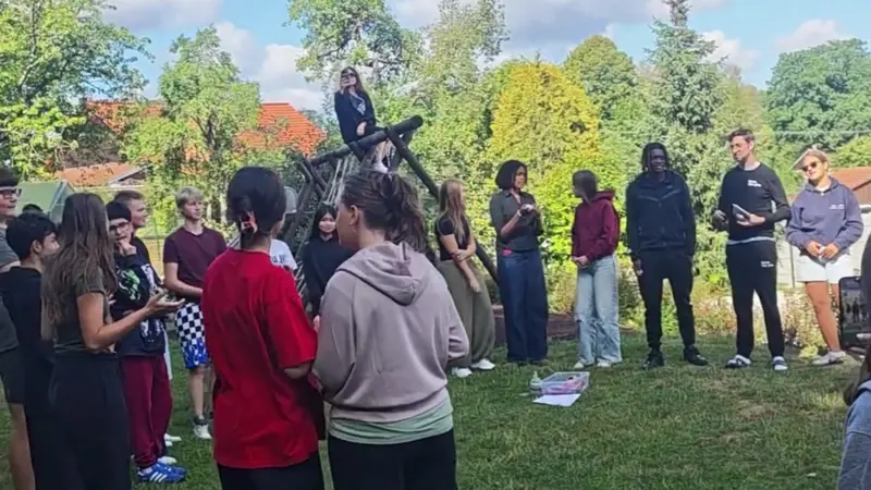 Participantes de cinco países en círculo durante una dinámica en el jardín del centro de Moravec