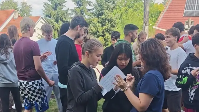 Participantes conversando por parejas con una hoja en la mano durante una actividad al aire libre
