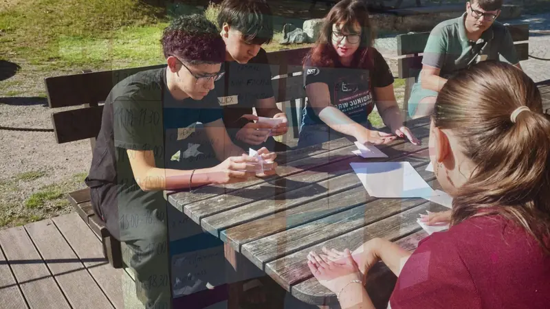 Participantes trabajando con papeles alrededor de una mesa de madera al sol