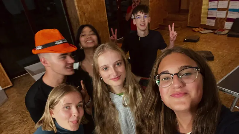 Selfie de un grupo de participantes de distintos países, uno con un sombrero naranja