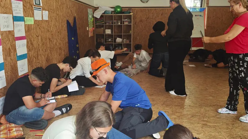 Participantes trabajando en el suelo de la sala con papeles y bolígrafos durante un taller
