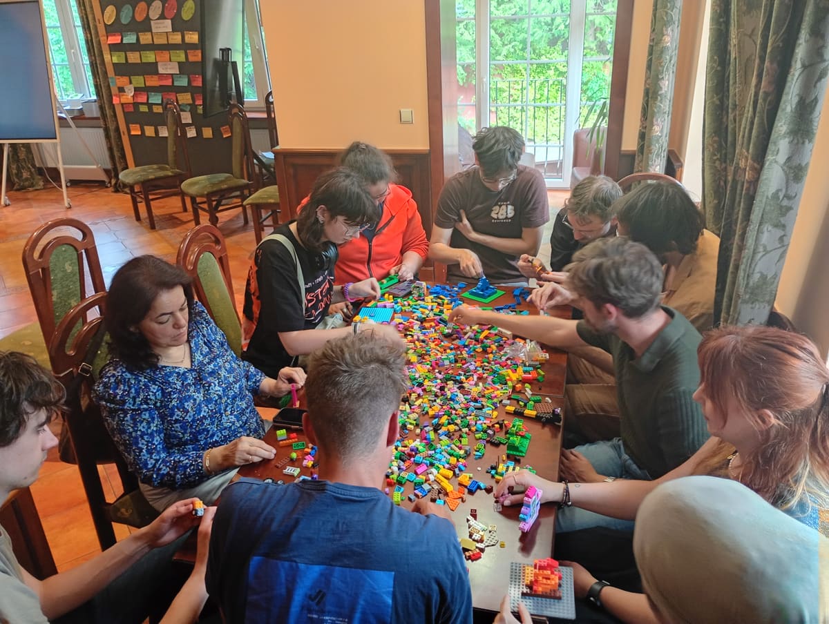 Participantes construyendo con LEGO alrededor de una mesa llena de piezas