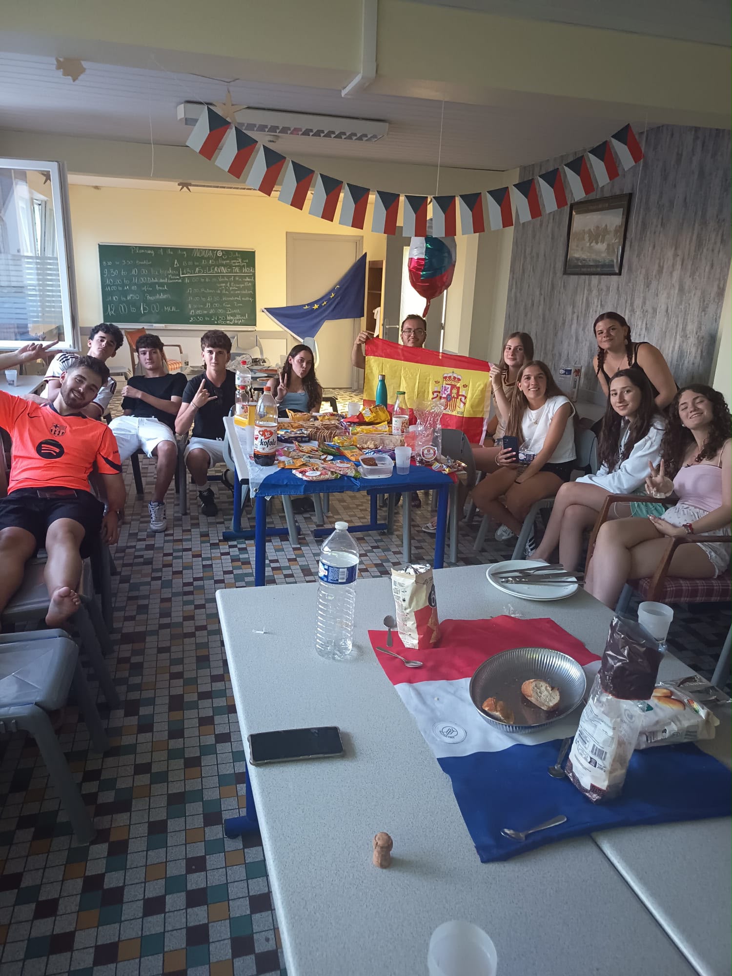 Velada intercultural en el centro, con banderas de España, República Checa y la Unión Europea y una mesa de aperitivos típicos